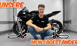 Ein Mann hockt neben einem Motorrad, das auf Montageständern steht. Perfekt, um das Motorrad hochzubocken!