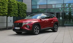 Roter Hyundai Tucson 2026 vor einem modernen Gebäude mit Bäumen.