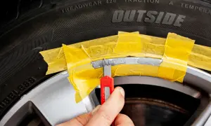 Felge kratzer entfernen kosten: Mit Klebeband wird die Felge maskiert, bevor ein Cutter zum Ausbessern von Kratzern angesetzt wird.