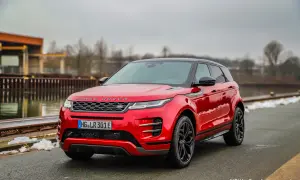 Roter Range Rover Evoque parkt am Wasser. Die Anhängelast ist für Abenteuer bereit.