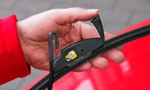 Hand wechselt Heckscheibenwischer. Ein kleiner Hebel muss gelöst werden, um den Wischerarm zu entfernen.