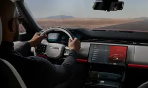Mann fährt Range Rover, steuert über das intuitive Land Rover InControl System. Die Ambientebeleuchtung "Dynamic Red" leuchtet.