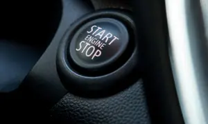 Nahaufnahme eines Start/Stop-Knopfes im Auto. Der Knopf ist schwarz mit rosa Schrift.