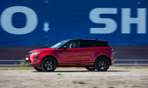 Roter Range Rover Evoque 2022 fährt an blauer Wand mit weißen Buchstaben vorbei.