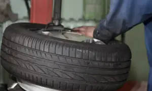 Ein Mechaniker wechselt einen Reifen. Die Frage "was kostet ein reifenwechsel" beschäftigt viele Autofahrer.