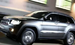 Grauer Jeep Grand Cherokee 3.0 CRD 250 PS in Bewegung, der auf der Straße fährt. Mögliche Probleme mit dem Motor sind hier nicht sichtbar.