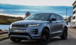 Grauer Range Rover Evoque, dessen Länge durch die dynamische Seitenansicht betont wird. Ein stilvolles SUV am Wasser.