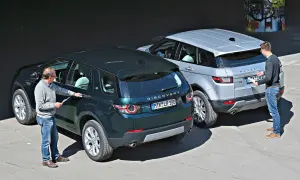 Zwei Männer inspizieren zwei Land Rover: einen dunklen Discovery Sport und einen silbernen Range Rover Evoque. Ein kleiner Land Rover, der Discovery Sport, steht im Vordergrund.