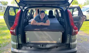 Frau liegt auf Bett im Dacia Jogger, bereit für den Camping-Test.