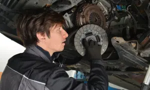 Mechaniker hält neue Kupplungsscheibe. Die Kosten für den Kupplung wechseln sind oft eine Überraschung.