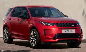 Roter Range Rover Discovery Sport, ein **range rover approved** Fahrzeug, parkt vor einer hellen Wand mit grünen Fensterläden.
