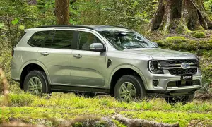 Silberner Ford Everest fährt durch grünen Wald in Deutschland.
