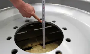 Finger zeigt auf Maßband, um die Felgenbreite zu messen.