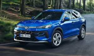 Blauer VW t roc fährt durch einen Wald.