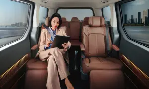 Frau arbeitet im luxuriösen Hyundai Staria Innenraum, während sie durch eine Stadt fährt.