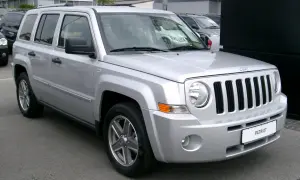 Silberner Jeep Patriot, der auf einem Parkplatz steht. Bekannt für seine Robustheit, aber auch für seine Jeep Patriot Schwachstellen, wie z.B. Rost an den Radläufen.
