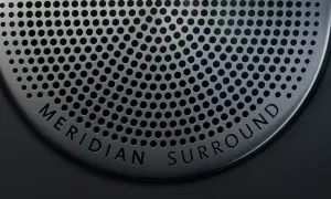 Nahaufnahme eines Lautsprechergitters mit der Aufschrift "MERIDIAN SURROUND". Gute Meridian Soundsystem Erfahrungen sind garantiert.