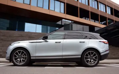 Silberner Range Rover Velar parkt vor moderner Architektur. Die eleganten Range Rover Velar Maße passen perfekt in das urbane Umfeld.