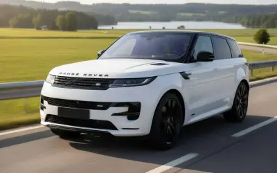 Ein weißer Range Rover Sport mit schwarzem Dach fährt auf einer Landstraße. Perfekt für ein Range Rover Abo.