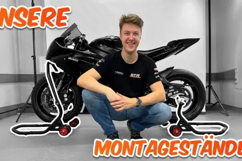 Ein Mann hockt neben einem Motorrad, das auf Montageständern steht. Perfekt, um das Motorrad hochzubocken!