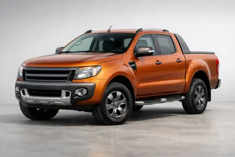 Orange Ford Ranger im Test. Der robuste Pickup steht auf einem grauen Untergrund vor hellem Hintergrund.