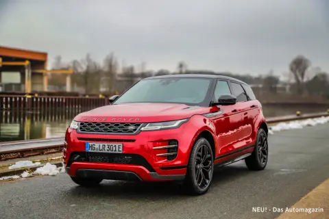 Roter Range Rover Evoque parkt am Wasser. Die Anhängelast ist für Abenteuer bereit.