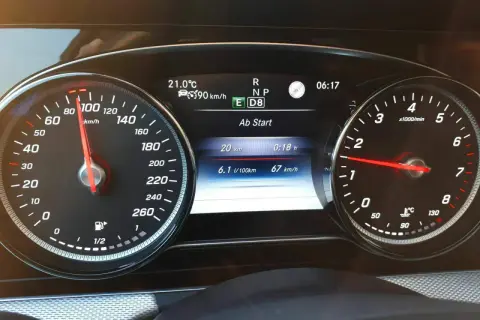 Fahrzeug-Display eines Mercedes mit Tacho bei 90 km/h, Verbrauchsanzeige und aktiver Tempomat-Funktion.