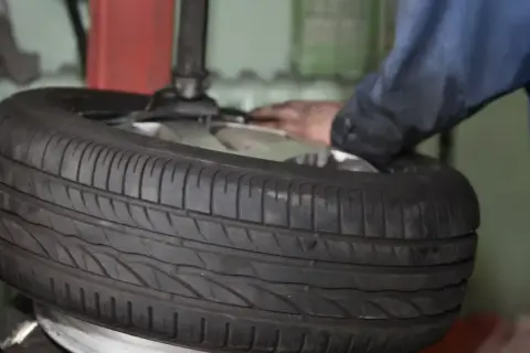 Ein Mechaniker wechselt einen Reifen. Die Frage "was kostet ein reifenwechsel" beschäftigt viele Autofahrer.