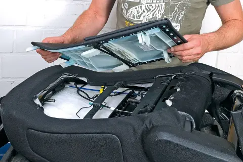 Ein Mann montiert eine Sitzfläche, um die Sitzheizung nachrüsten zu können. Die Kosten dafür sind überschaubar.