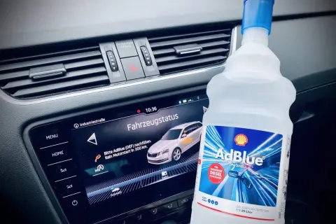 Flasche AdBlue neben dem Armaturenbrett. Fahrzeugstatus zeigt "Bitte AdBlue nachfüllen. Kein Motorstart in 300 km.