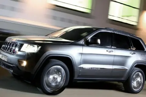 Grauer Jeep Grand Cherokee 3.0 CRD 250 PS in Bewegung, der auf der Straße fährt. Mögliche Probleme mit dem Motor sind hier nicht sichtbar.