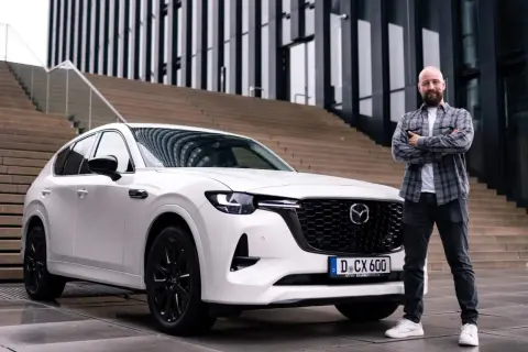 Mann steht neben weißem Mazda CX-60. Der Wagen ist bereit für den Mazda CX-60 Test.