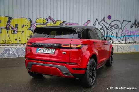 Ein glänzender, **range rover rot** steht vor einer Graffiti-Wand. Das Auto hat ein schwarzes Dach und schwarze Felgen.