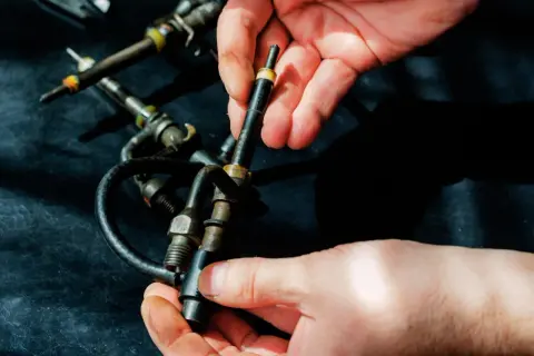 Hände halten Diesel-Einspritzdüsen. Ein Grund, warum der Motor ruckelt im Stand, könnte eine defekte Düse sein.