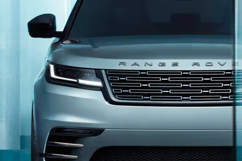 Der Kühlergrill eines silbernen Range Rover mit dem Schriftzug "RANGE ROVER" und dem Land Rover Logo. Ein Fahrzeug, das "land rover approved" ist.