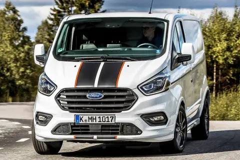Weißer Ford Transit Custom mit Sportstreifen, Fahrer im Blick. Keine Probleme hier, nur ein stilvoller Transporter auf der Straße.