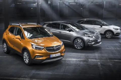 Drei Opel-Modelle in einem Parkhaus: ein orangefarbener Mokka, ein grauer Grandland X und ein weißer Crossland X. Ein Ausblick auf die Opel Modelle 2026.