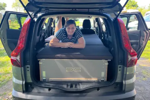 Frau liegt auf Bett im Dacia Jogger, bereit für den Camping-Test.