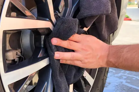 Hand poliert Felge mit schwarzem Tuch. Ein einfacher felgenreiniger hausmittel-Trick für glänzende Räder.
