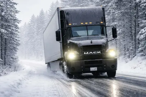 Schwarzer Mack-LKW fährt durch verschneiten Wald. Vorsicht: kann AdBlue einfrieren, was zu Problemen führen kann.