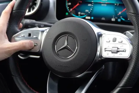 Hand stellt Mercedes Distronic ein. Lenkrad mit Bedienelementen und Stern-Logo.