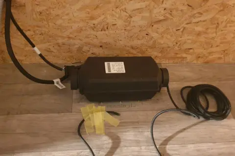 Einbau einer Standheizung: Das Gerät mit Kabeln liegt auf dem Boden, bereit für die Installation.