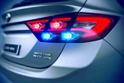 Rückansicht eines Autos mit leuchtenden roten Bremslichtern und blauen Akzentlichtern. Die dynamische Bremsleuchte sorgt für Sichtbarkeit.