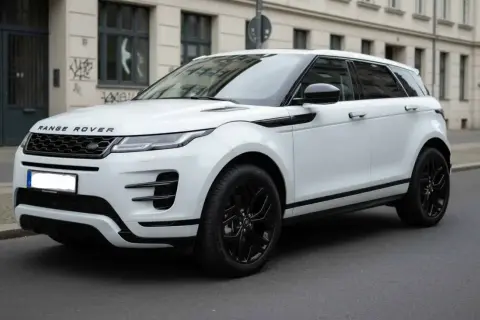 Ein weißer Range Rover klein mit schwarzen Felgen steht auf einer Straße vor einem Gebäude.