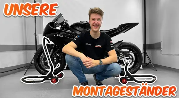 Ein Mann hockt neben einem Motorrad, das auf Montageständern steht. Perfekt, um das Motorrad hochzubocken!