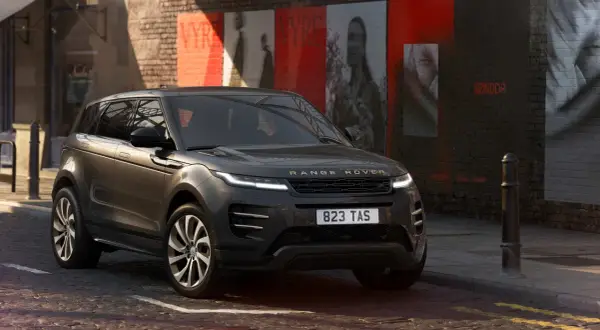 Dunkelgrauer Range Rover Evoque Black Edition parkt in einer Gasse mit Graffiti an der Wand.