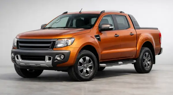 Orange Ford Ranger im Test. Der robuste Pickup steht auf einem grauen Untergrund vor hellem Hintergrund.