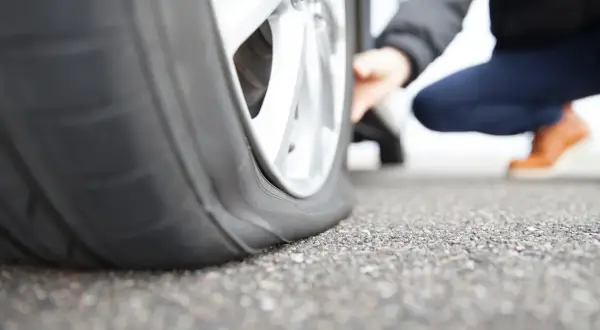 Ein Auto mit platten Reifen steht auf Asphalt. Die Frage ist, wie lange kann ein Auto auf einem platten Reifen stehen, bevor es beschädigt wird?