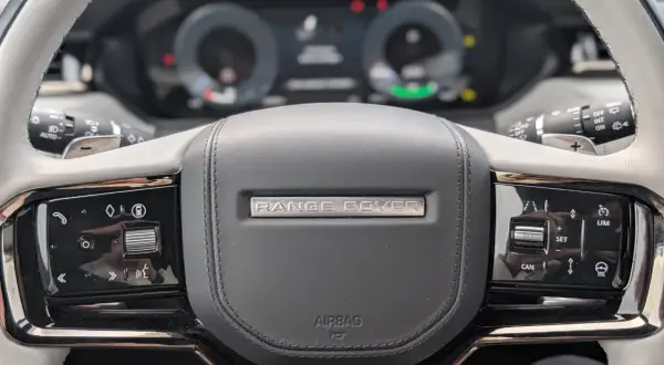 Nahaufnahme des **Range Rover Lenkrads** mit Bedienelementen für Tempomat und Infotainment.