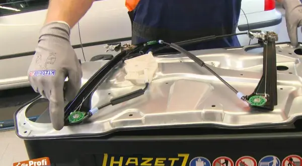 Kfz-Mechaniker lernt Fensterheber nach Batteriewechsel an. Einbau eines neuen Fensterhebersystems.